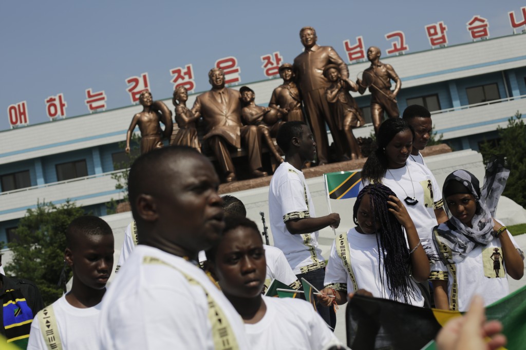 Students from the Laureat International School in Tanzania walk past a statue of the late North Korean leaders Kim Il Sung and Kim Jong Il, surrounded by children, on the parade square of the Songdowon International Children's Camp, Tuesday, July 29, 2014, in Wonsan, North Korea. The camp, which has been operating for nearly 30 years, was originally intended mainly to deepen relations with friendly countries in the Communist or non-aligned world.  (AP Photo/Wong Maye-E)