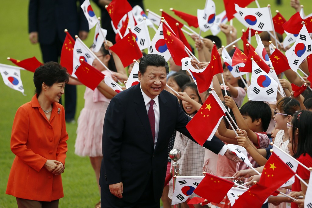 Chinese President Xi Jinping (C) and South Korean president Park Geun-hye (L) greets children waving the two national flags during a welcoming ceremony at the presidential Blue House in Seoul July 3, 2014.  (AP Photo/Kim Hong-ji, Pool)   