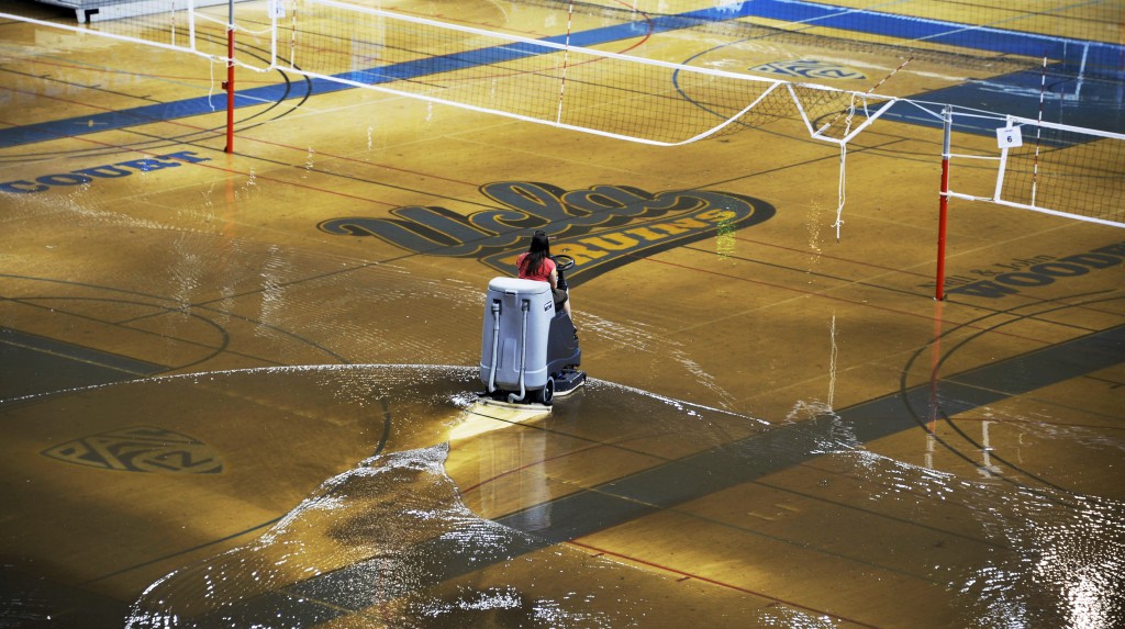 A worker begins the task of cleaning up at least an inch of water covering the playing floor at Pauley Pavilion, home of UCLA basketball, after a broken 30-inch water main under nearby Sunset Boulevard caused flooding that inundated several areas of the UCLA campus in the Westwood section of Los Angeles on Tuesday, July 29, 2014. (AP Photo/Mike Meadows)