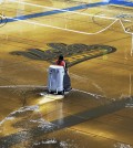 A worker begins the task of cleaning up at least an inch of water covering the playing floor at Pauley Pavilion, home of UCLA basketball, after a broken 30-inch water main under nearby Sunset Boulevard caused flooding that inundated several areas of the UCLA campus in the Westwood section of Los Angeles on Tuesday, July 29, 2014. (AP Photo/Mike Meadows)