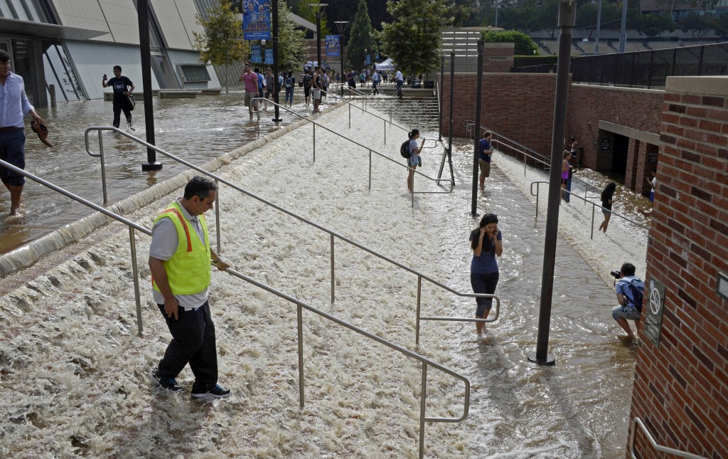 People walk down a stairway leading to a parking structure across from Pauley Pavilion on the UCLA campus after flooding from a broken 30-inch water main under nearby Sunset Boulevard inundated a large area of the campus in the Westwood section of Los Angeles, Tuesday, July 29, 2014. The 30-inch (75-centimeter) 93-year-old pipe that broke made a raging river of the street and sent millions of gallons (liters) of water across the school's athletic facilities, including the famed floor of Pauley Pavilion, the neighboring Wooden Center and the Los Angeles Tennis Center, and a pair of parking structures that took the brunt of the damage. (AP Photo/Mike Meadows)