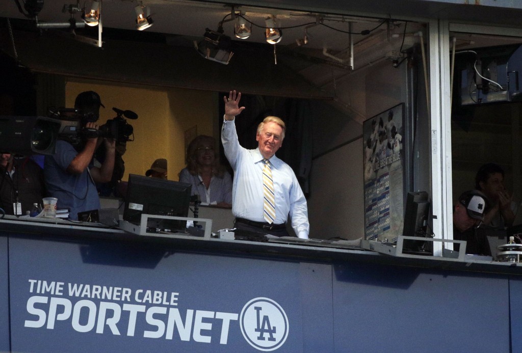 Broadcaster Vin Scully acknowledges the crowd at Dodger Stadium during a baseball game between the Los Angeles Dodgers and the Atlanta Braves on Tuesday, July 29, 2014, in Los Angeles. The Dodgers announced that Scully will remain with the team for the 2015 season. (AP Photo/Jae C. Hong)