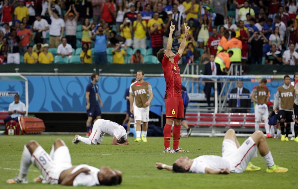 Exhausted US players lie on the ground as Belgium's Axel Witsel (6) celebrates at the end of the extra time during the World Cup round of 16 soccer match between Belgium and the USA at the Arena Fonte Nova in Salvador, Brazil, Tuesday, July 1, 2014. Belgium held on to beat US 2-1 in extra time.(AP Photo/Felipe Dana)