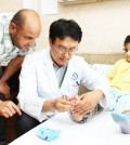 Amer Alwan Ibreesam, left, looks on as professor Cho Jae-ho of Ajou University Hospital examines the leg of his daughter Tiba at the hospital in Suwon, Gyeonggi Province. Hanwha Engineering and Construction brought Tiba from Iraq to get surgery on her leg in Korea. (Courtesy of Hanwha Engineering and Construction)