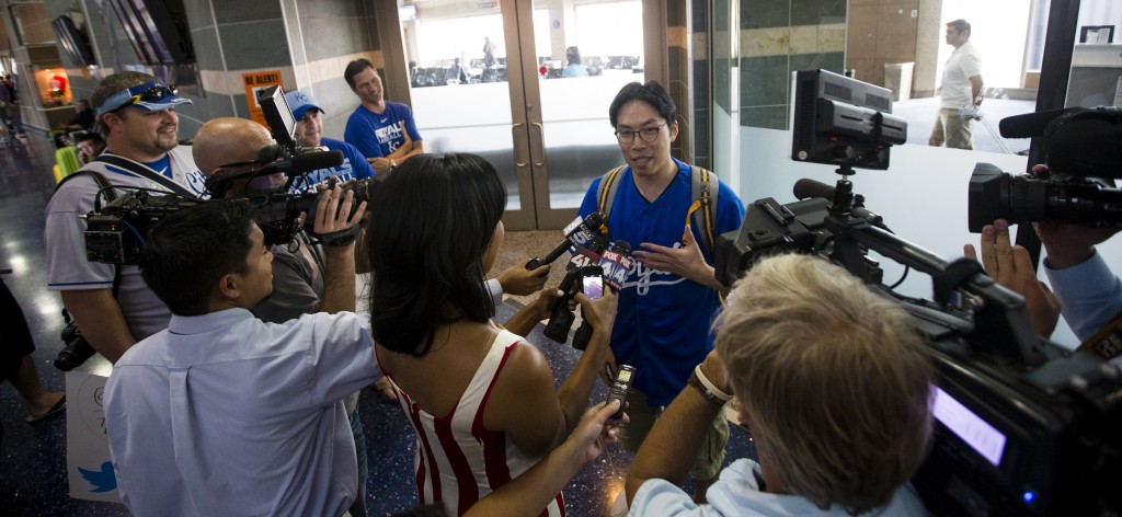 Sung Woo Lee, center, speaks to the local media after arriving at Kansas City International Airport Tuesday, Aug. 5, 2014. Lee is a Kanas City Royals fan from South Korea and came to Kansas City to see his first Royals game. He will see five games and throw out the first pitch on Monday (AP Photo/The Kansas City Star, Brian Davidson)