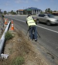 A cameraman films a broken power pole along the highway after a fatal crash Friday, Aug. 22, 2014, in Oceanside, Calif. Three Japanese college students were killed and five other foreign students were injured when a car carrying them veered off a California freeway and struck a power pole, officials said Friday. (AP Photo/Gregory Bull)