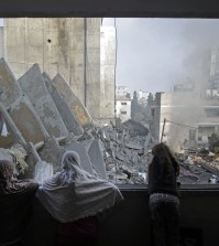 A Palestinian family looks from a window to the rubble of the collapsed 15-story Basha Tower following early morning Israeli airstrikes in Gaza City, Tuesday, Aug. 26, 2014. Israel bombed two Gaza City high-rises with dozens of homes and shops Tuesday, collapsing the 15-story Basha Tower and severely damaging the Italian Complex in a further escalation in seven weeks of cross-border fighting with Hamas. (AP Photo/Khalil Hamra)