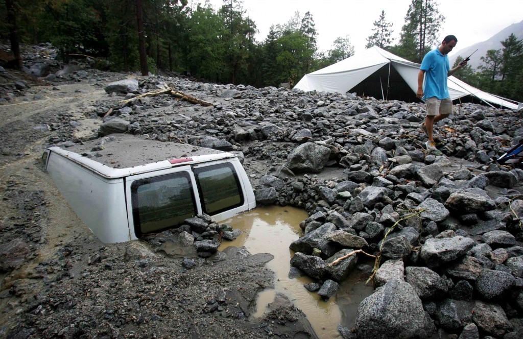 An official of Forest Home Christian Conference Center in Forest Falls, Calif., inspects damage on the property following thunderstorms on Sunday, Aug. 3, 2014. About 1,500 residents of Oak Glen, and another 1,000 residents of Forest Falls in the San Bernardino Mountains were unable to get out because the roads were covered with mud, rock and debris, authorities said. (AP Photo/The Press-Enterprise, David Bauman)