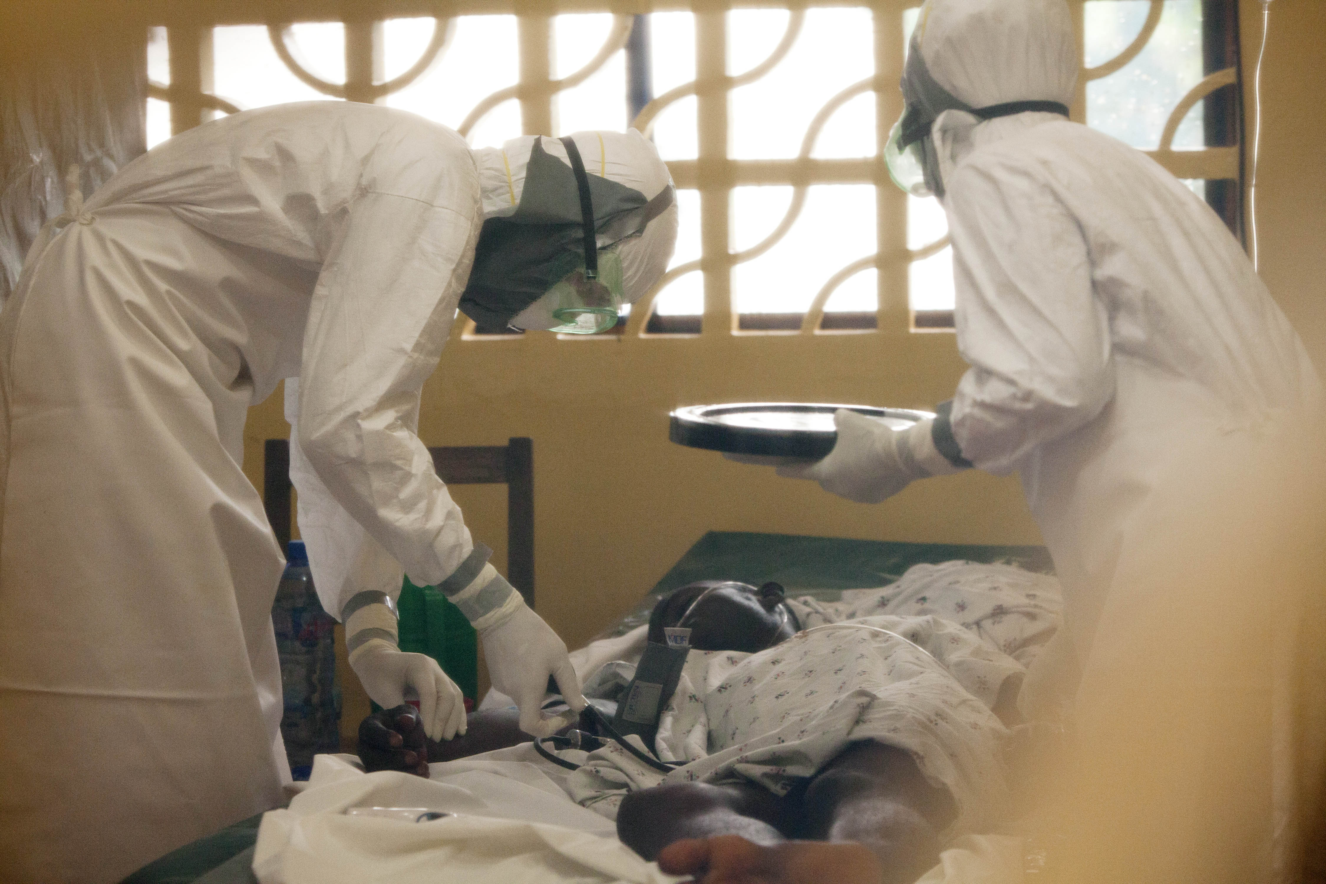 In this 2014 photo provided by the Samaritan's Purse aid organization, Dr. Kent Brantly, left, treats an Ebola patient at the Samaritan's Purse Ebola Case Management Center in Monrovia, Liberia. On Saturday, July 26, 2014, the North Carolina-based aid organization said Brantly tested positive for the disease and was being treated at a hospital in Monrovia. (AP Photo/Samaritan's Purse)