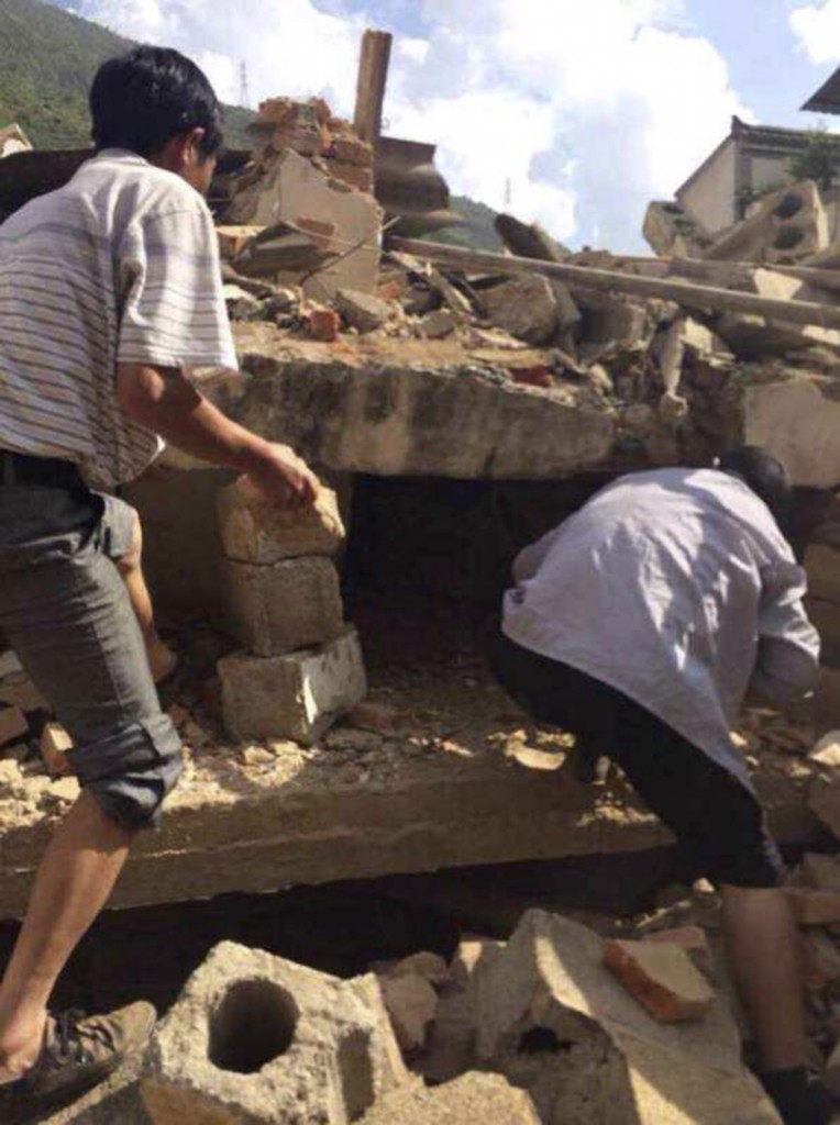 In this photo taken by cellphone and released by China's Xinhua News Agency, men at rubbles of buildings look for survivors after an earthquake in Ludian County of Zhaotong City in southwest China's Yunnan Province Sunday, Aug. 3, 2014. A strong earthquake rattled southwest China on Sunday, knocking out communication and power lines and causing people to rush out of buildings, but there were no immediate reports of injuries. (AP Photo/Xinhua/Hu Chao)  