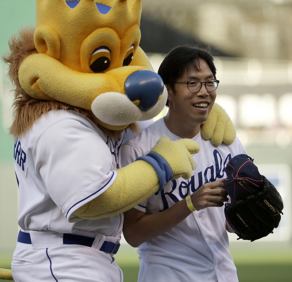 Longtime Kansas City Royals fan Sung Woo Lee, from South Korea, celebrates with Royals mascot Sluggerrr after throwing out the ceremonial first pitch before a baseball game against the Oakland Athletics, Monday, Aug. 11, 2014, in Kansas City, Mo. (AP Photo/Charlie Riedel)