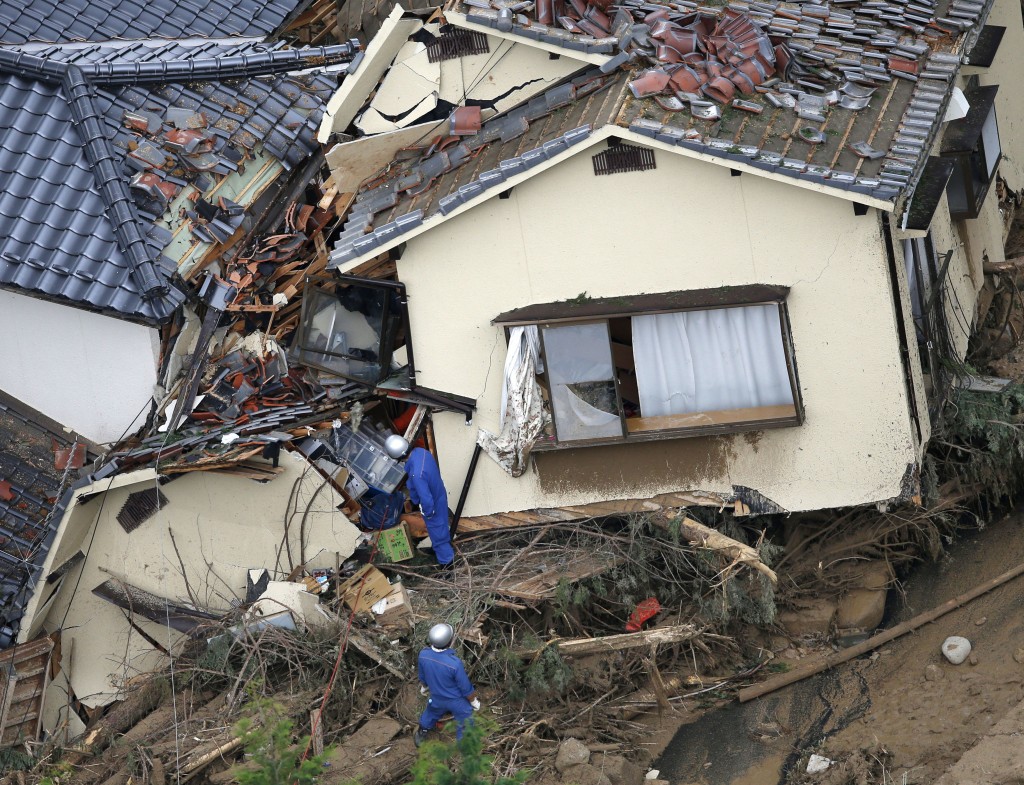 In this aerial photo, rescue workers search for survivors in an area devastated by a massive landslide which swept through residential areas in Hiroshima, western Japan, Wednesday, Aug. 20, 2014. A several people died and at least a dozen were missing after rain-sodden hills in the outskirts of Hiroshima gave way early Wednesday in several landslides. (AP Photo/Kyodo News) 