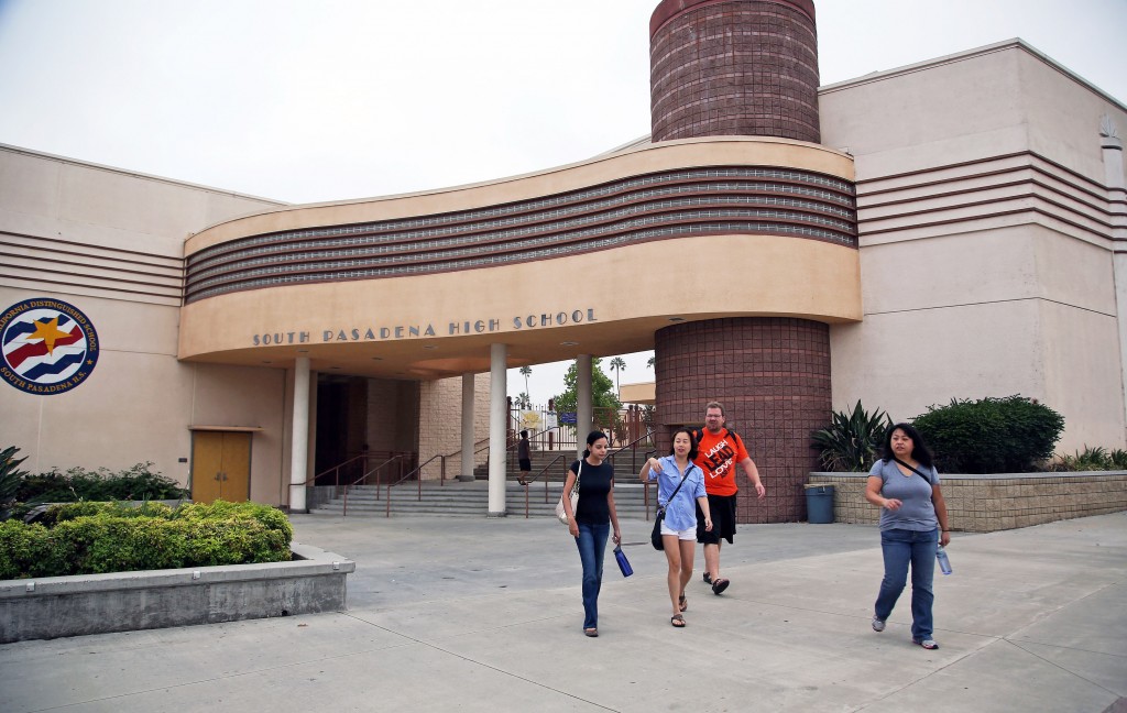 People walk past South Pasadena, Calif., High School Tuesday, Aug. 19, 2014, after authorities announced the arrest of two high school students suspected of planning a massacre at the school after investigators monitored their Internet activities. South Pasadena police chief Arthur Miller said that school officials had heard about the plot and informed police, who determined the threat was credible. Police say the boys, ages 16 and 17, didn't have weapons but were researching automatic weapons and explosives, especially propane. (AP Photo/Nick Ut)