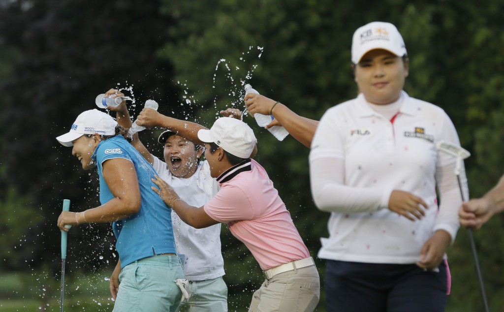 Lee Mi-rim of South Korea, left, is doused with water by other players and friends as Inbee Park, right, walks off the green after the second playoff hole of the final round during the Meijer LPGA Classic golf tournament at Blythefield Country Club, Sunday, Aug. 10, 2014, in Belmont, Mich. (AP Photo/Carlos Osorio)