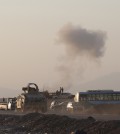 An armored vehicle belonging to Kurdish Peshmerga fighters rushes to a bombing site as smoke rises after airstrikes targeting Islamic State militants near the Khazer checkpoint outside of the city of Irbil in northern Iraq, Friday, Aug. 8, 2014. The Iraqi Air Force has been carrying out strikes against the militants, and for the first time on Friday, U.S. war planes have directly targeted the extremist Islamic State group, which controls large areas of Syria and Iraq.(AP Photo/ Khalid Mohammed)