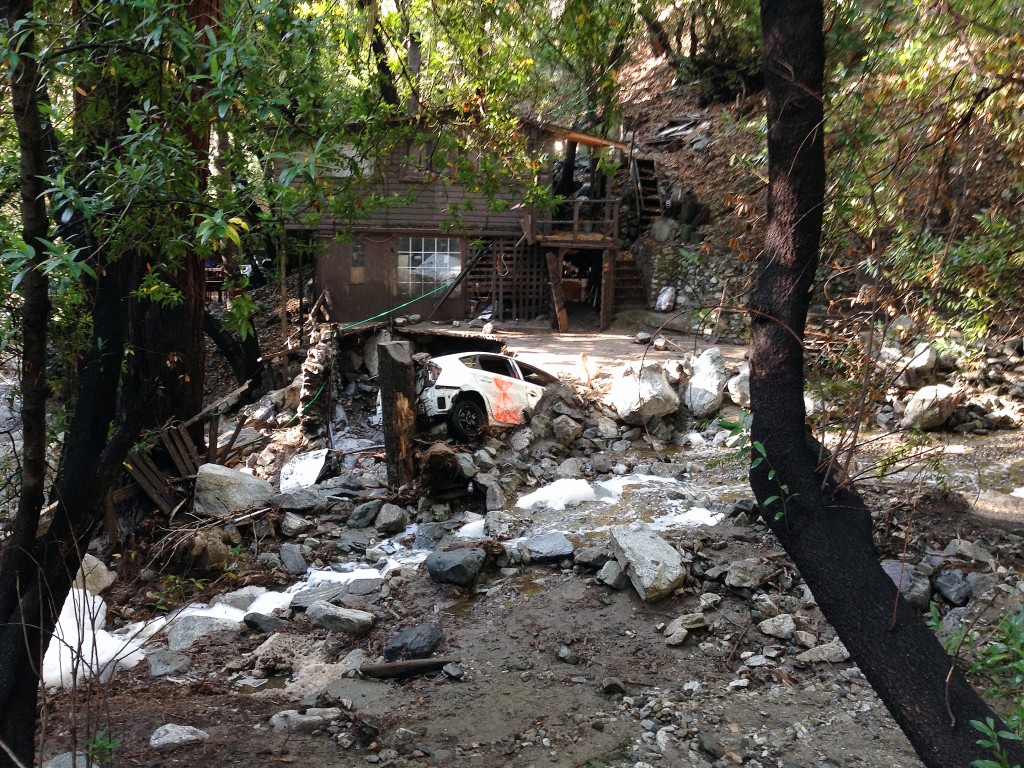 A car is lodged in the debris on Monday, Aug. 4, 2014, where a body was found Sunday that was swept into the rain-swollen water course in Mount Baldy, Calif. About 2,500 people were stranded early Monday after thunderstorms caused mountain mudslides in Southern California. (AP Photo/Brian Melley)