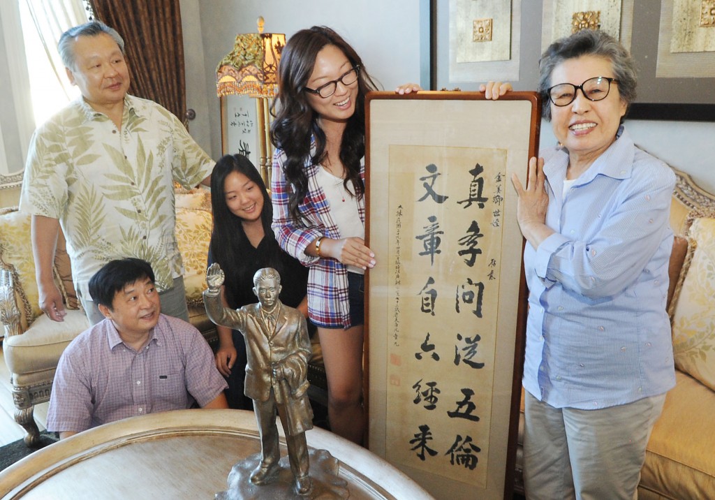 Kim Mi-kyung, far right, holds a scroll given to her by independence fighter Kim Gu as she stands with her grandchildren. (Park Sang-hyuk/The Korea Times)