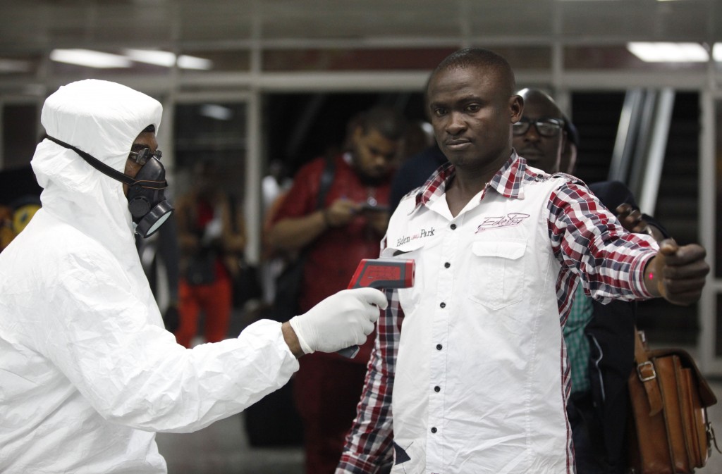 A Nigerian port health official uses a thermometer on a worker at the arrivals hall of Murtala Muhammed International Airport in Lagos, Nigeria, Wednesday, Aug. 6, 2014. A Nigerian nurse who treated a man with Ebola is now dead and five others are sick with one of the world's most virulent diseases, authorities said Wednesday, as the death toll rose to at least 932 people in four West African countries. (AP Photo/Sunday Alamba)