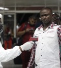 A Nigerian port health official uses a thermometer on a worker at the arrivals hall of Murtala Muhammed International Airport in Lagos, Nigeria, Wednesday, Aug. 6, 2014. A Nigerian nurse who treated a man with Ebola is now dead and five others are sick with one of the world's most virulent diseases, authorities said Wednesday, as the death toll rose to at least 932 people in four West African countries. (AP Photo/Sunday Alamba)