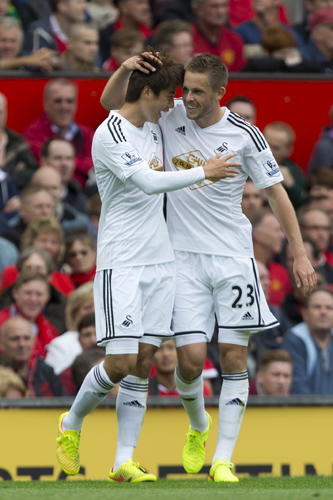 Swansea City's Ki Sung-Yeung, left, celebrates with teammate Gylvi Sigurdsson after scoring against Manchester United during their English Premier League soccer match at Old Trafford Stadium, Manchester, England, Saturday Aug. 16, 2014. (AP Photo/Jon Super)