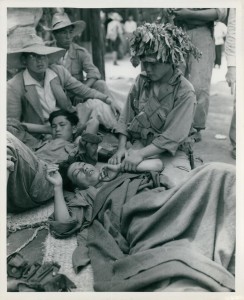 The caption on the back reads: "A South Korean soldier aids a wounded buddy before he is evacuated to the rear. 1 July 1950." (Official Department of Defense photo)