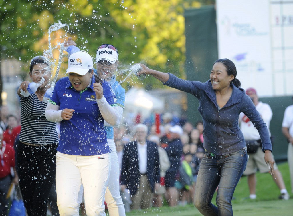 Jenny Shin, left, Meena Lee, center, and Illhee Lee, right, spray Champion Inbee Park after she won the Wegmans LPGA golf championship in Pittsford, N.Y., Sunday, Aug. 17, 2014. Park won in a sudden death playoff round. (AP Photo/Gary Wiepert)