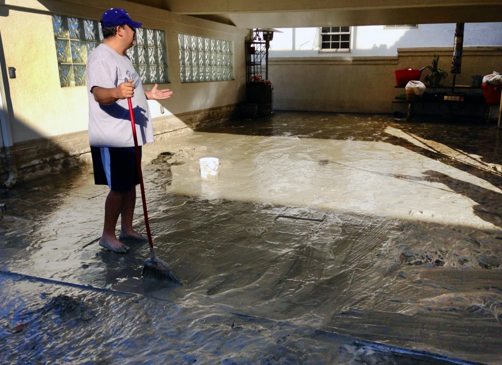 Hector Brown sweeps out his aunt and uncle's house in Seal Beach, Calif. on Wednesday, Aug. 27, 2014. The entire house and garage was flooded by a foot of water and muddy sand late Tuesday night after low-lying streets in the Southern California coastal community was inundated by a surge of rising seawater brought on by Hurricane Marie spinning off Mexico's Pacific coast. (AP Photo/Gillian Flaccus)
