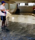 Hector Brown sweeps out his aunt and uncle's house in Seal Beach, Calif. on Wednesday, Aug. 27, 2014. The entire house and garage was flooded by a foot of water and muddy sand late Tuesday night after low-lying streets in the Southern California coastal community was inundated by a surge of rising seawater brought on by Hurricane Marie spinning off Mexico's Pacific coast. (AP Photo/Gillian Flaccus)