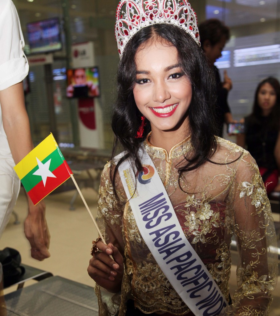 FILE - In this June 5, 2014 file photo, Myanmar model May Myat Noe, winner of Miss Asia Pacific World 2014 pageant, waves a miniature flag of the country upon her arrival at Yangon International Airport in Yangon, Myanmar. The first Myanmar national to win an international pageant has been stripped of her title for being rude and dishonest, and has allegedly run off with the expensive crown and breast implants. (AP Photo/Khin Maung Win)