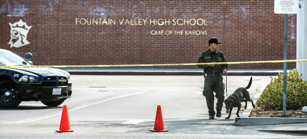 Local law enforcement along with a dog searches in front of Fountain Valley High School, Wednesday, Sept. 3, 2014, after an email was sent to an English/journalism teacher threatening students and teachers at the school. (AP Photo/The Orange County Register, Mark Rightmire)