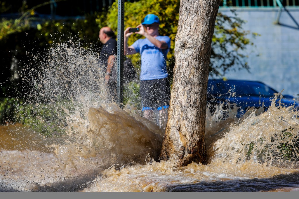 People stopped to take pictures of flowing water along North Olive Drive, following a water main break on Sunset Boulevard, in West Hollywood, Friday, Sept. 26, 2014. (AP Photo/Los Angeles Times, Jay L. Clendenin)