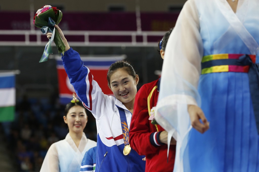 Gold medallist North Korea's Hong Un-jong raises her flower bouquet at the end of the medal ceremony for the gymnastics women's vault final at the 17th Asian Games in Incheon, South Korea, Wednesday, Sept. 24, 2014. (AP Photo/Kin Cheung)