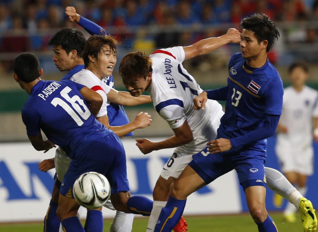 South Korea's Kim Seung-dae, center, fights for the ball with Thailand's Narubadin Weerawatnodom, right and Adison Promrak, left, during the men's football semifinal against Thailandat the 17th Asian Games in Incheon, South Korea, Tuesday, Sept. 30, 2014. (AP Photo/Kin Cheung)