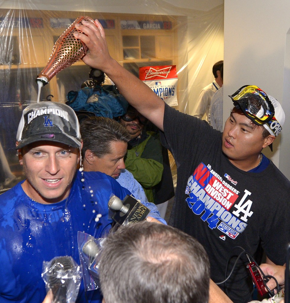 Los Angeles Dodgers' A.J. Ellis, left, is doused with champagne by Hyun-Jin Ryu, of South Korea after they defeated the San Francisco Giants 9-1 and clinching the National League West Division title in a baseball game, Wednesday, Sept. 24, 2014, in Los Angeles. (AP Photo/Mark J. Terrill)