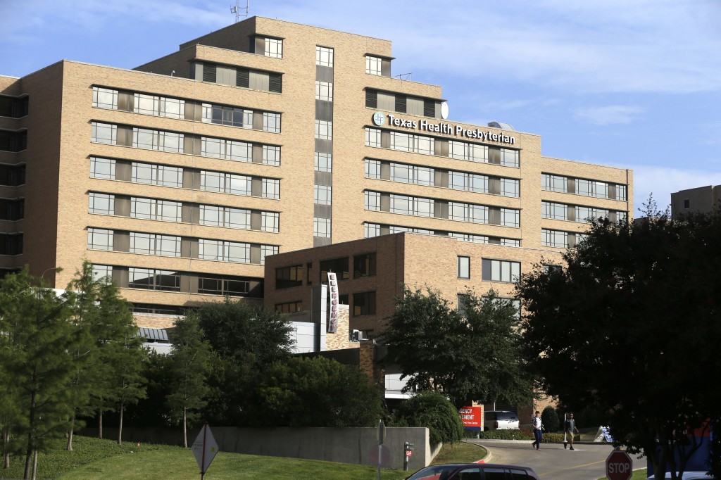Pedestrians walk outside Texas Health Presbyterian Hospital in Dallas, Tuesday, Sept. 30, 2014.  A patient in the hospital is showing signs of the Ebola virus and is being kept in strict isolation with test results pending, hospital officials said Monday. (AP Photo/LM Otero)
