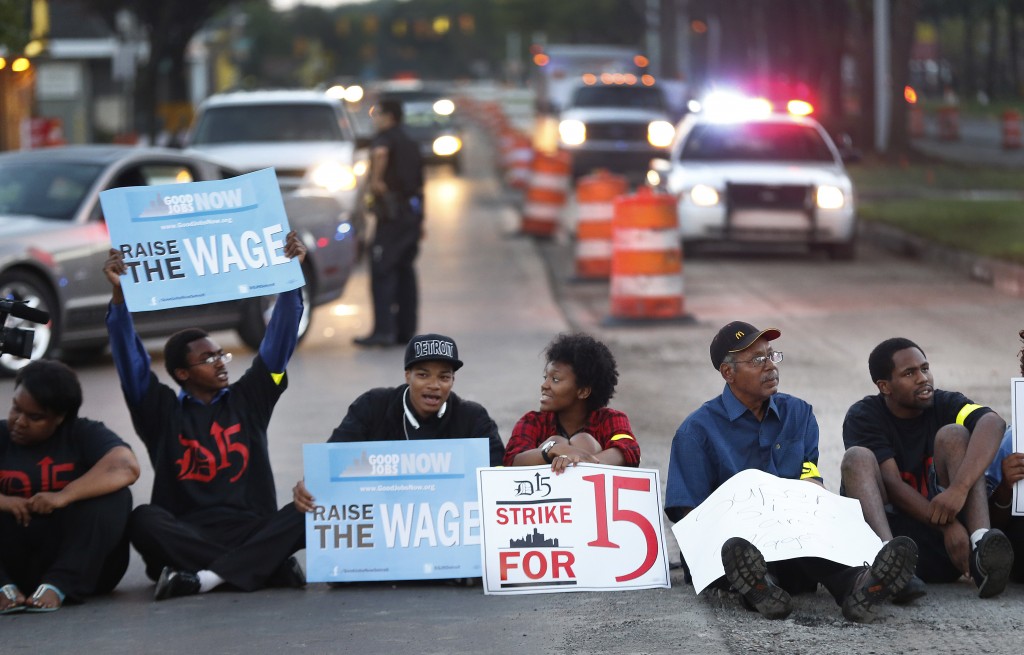 Protesters block traffic on Mack Avenue in Detroit as part of a national protest to push fast-food chains to pay their employees at least $15 an hour Thursday, Sept. 4, 2014. Hundreds of workers from McDonald's, Taco Bell, Wendy's and other fast-food chains are expected to walk off their jobs Thursday, according to labor organizers of the latest national protest to push the companies to pay their employees at least $15 an hour. (AP Photo/Paul Sancya)
