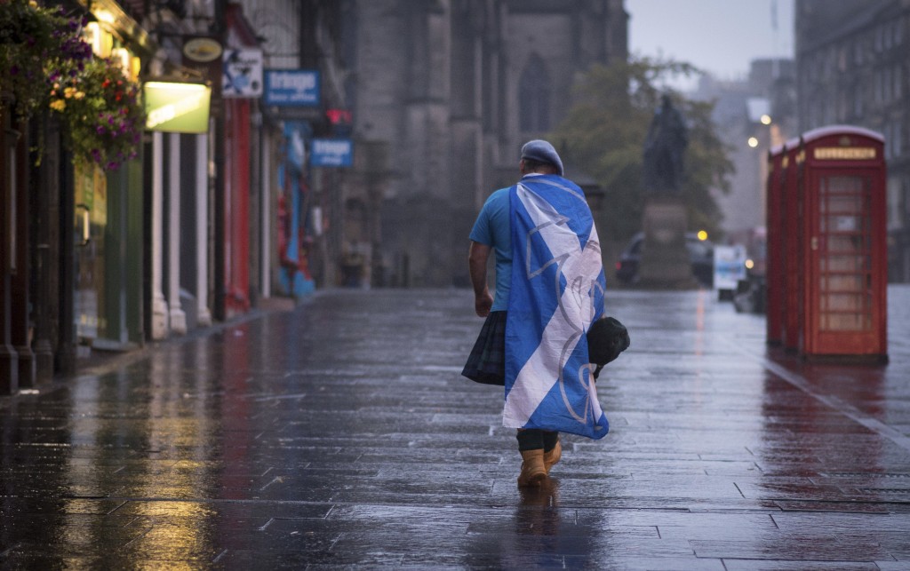 A lone YES campaign supporter walks down a street in Edinburgh after the result of the Scottish independence referendum, Scotland, Friday, Sept. 19, 2014. Scottish voters have rejected independence and decided that Scotland will remain part of the United Kingdom. The result announced early Friday was the one favored by Britain's political leaders, who had campaigned hard in recent weeks to convince Scottish voters to stay. It dashed many Scots' hopes of breaking free and building their own nation. (AP Photo/PA, Stefan Rousseau)