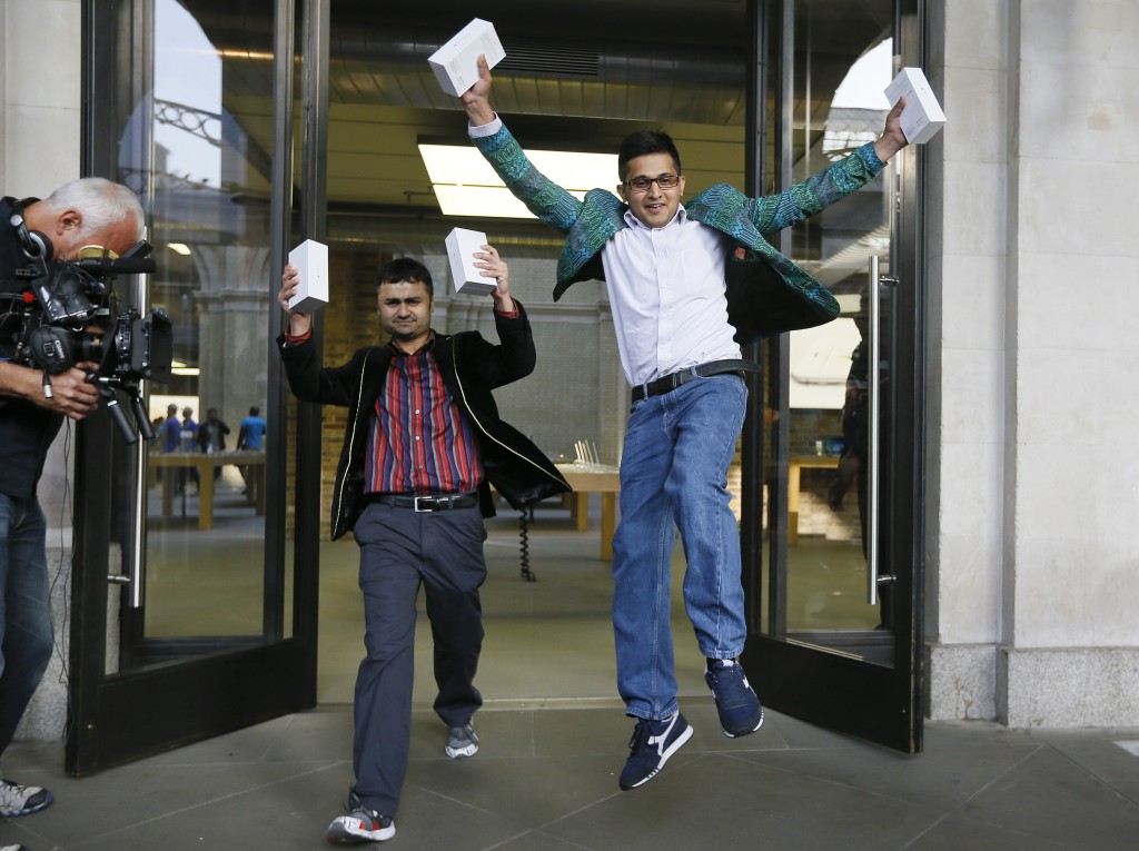 The first people in the queue, Sam Sheikh, left, and Jameel Ahmed, right, celebrate for the media after buying the new iPhone6, outside the Apple shop in London, Friday, Sept. 19, 2014. The new Apple iPhone6 went on sale at the shop on Friday. (AP Photo/Kirsty Wigglesworth)