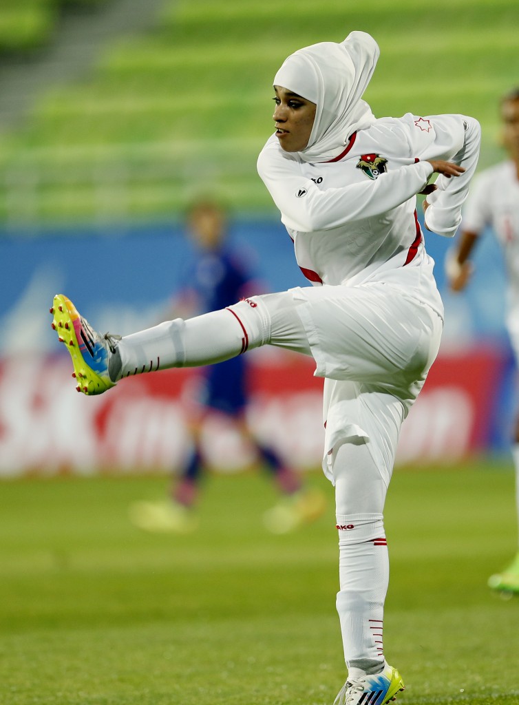 FILE- In this Sept. 18, 2014 file photo Jordan's Anfal Nayef Hammad Alsufy kicks a ball down filed during her team's football match against Japan at the 17th Asian Games in Incheon, South Korea. Qatar's delegation chief says the women's basketball team has withdrawn from the Asian Games after organizers refused to let players wear hijabs in competition. (AP Photo/Kin Cheung,File)