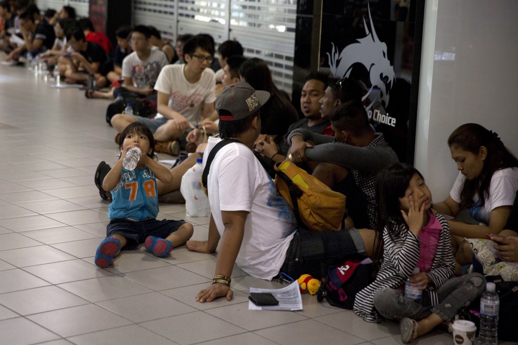 Shoppers wait inline to buy Apple's latest iPhones outside a reseller in Singapore, Friday, Sept. 19, 2014. Apple's newest mobile devices, the iPhone 6 and iPhone 6 Plus go on sale Friday. (AP Photo/Ng Han Guan)