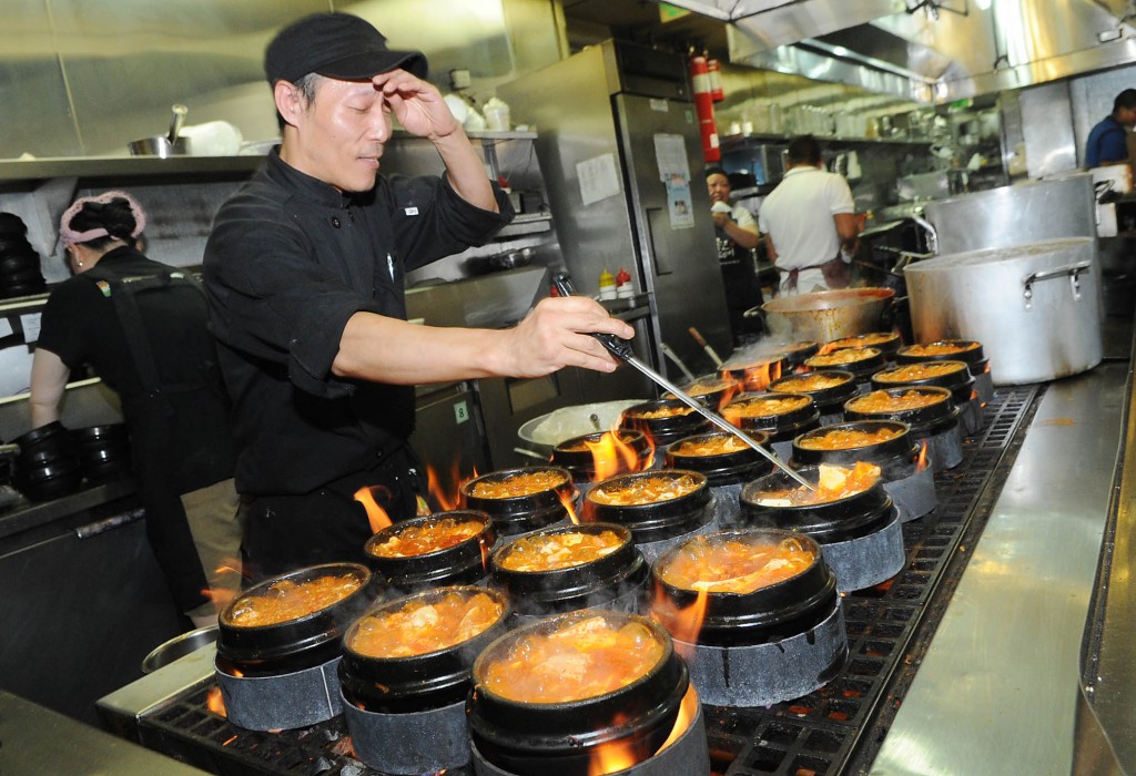 An employee at BCD Tofu House stirs boiling dishes. (Park Sang-hyuk/The Korea Times)