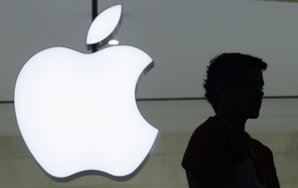 FILE - In a Wednesday, Dec. 7, 2011, file photo, a person stands near the Apple logo at the company's store in Grand Central Terminal, in New York. There's a shadowy global industry devoted to unlocking phones and extracting their information. For digital forensics companies, success can mean big bucks in the form of government contracts. And the notoriety that could come with cracking an iPhone used by a purported terrorist could rocket them to cyber stardom. (AP Photo/Mark Lennihan, File)