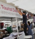 People from Korea Tourist Souvenir Expo are putting up a banner on their booth.  (The Korea Times / Park Sang-hyuk)