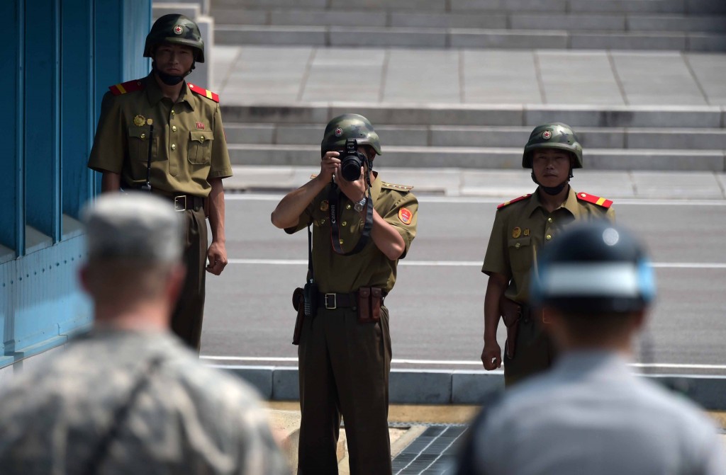 A North Korean soldier takes picture of an American soldier and a Korean military police officer at Panmujeom. (Newsis)