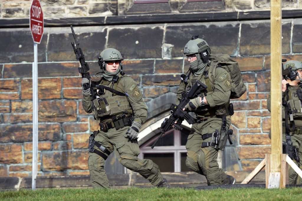 A Royal Canadian Mounted Police intervention team responds to a reported shooting at Parliament building in Ottawa, Wednesday, Oct. 22, 2014. A soldier standing guard at the National War Memorial has been shot by an unknown gunman and there have been reports of gunfire inside the halls of Parliament. (AP Photo/The Canadian Press, Adrian Wyld)