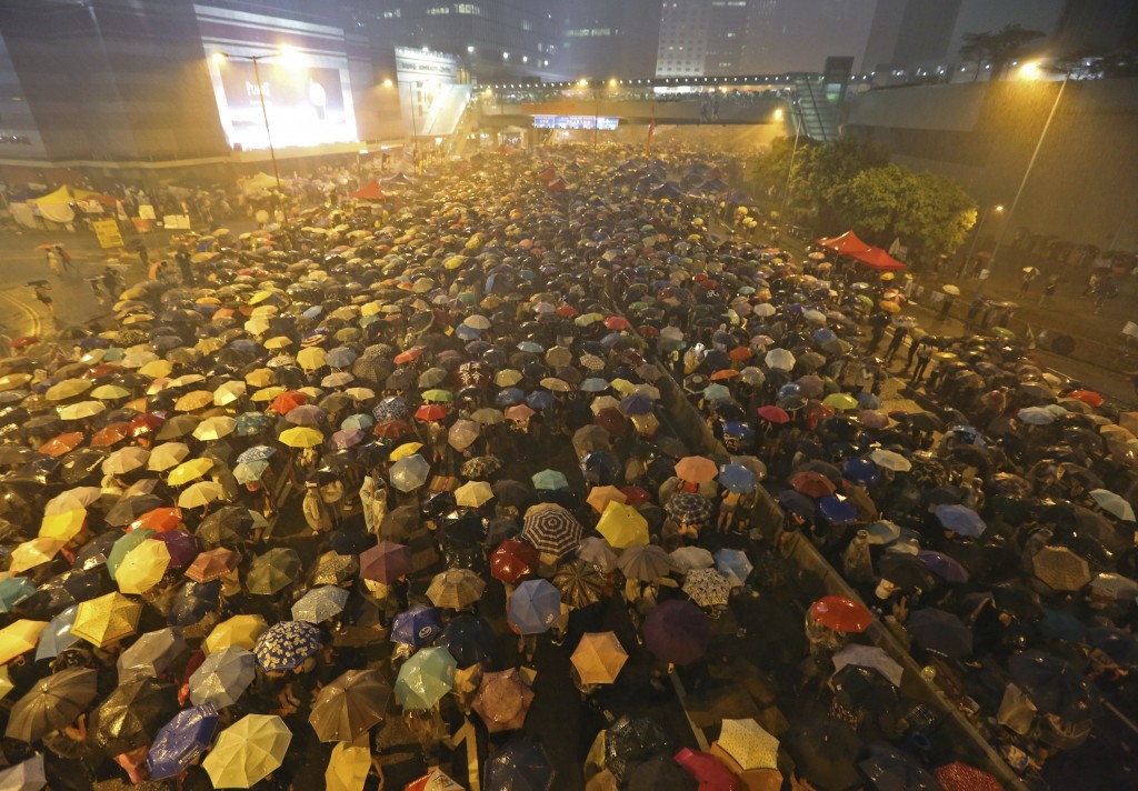 Pro-democracy protesters hold umbrellas under heavy rain in a main street near the government headquarters in Hong Kong, late Tuesday, Sept. 30, 2014. Pro-democracy protesters demanded that Hong Kong's top leader meet with them on Tuesday and threatened wider actions if he did not, after he said China would not budge in its decision to limit voting reforms in the Asian financial hub. (AP Photo)
