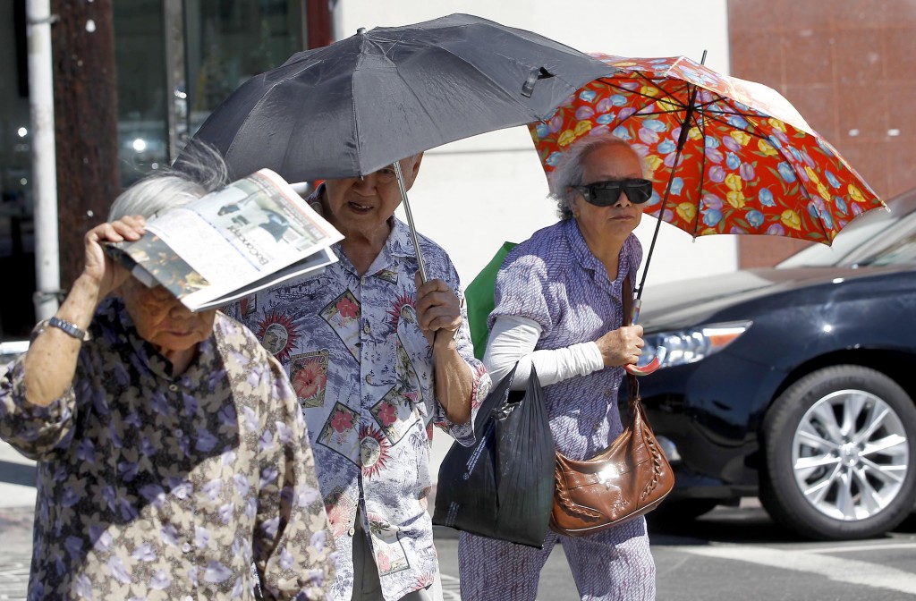 Women shade themselves from the sun in the Chinatown section of downtown Los Angeles on Thursday, Oct 2, 2014. Rising temperatures, falling humidity levels and Santa Ana winds increased fire danger in drought-stricken Southern California on Thursday, and forecasters said the fall heat wave would push temperatures well above normal from San Diego to San Francisco. (AP Photo/ Nick Ut)