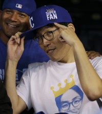 Kansas City Royals fan Sung Woo Lee, from South Korea, shows off his "super fan' cap before Game 1 of baseball's World Series between the Kansas City Royals and the San Francisco Giants Tuesday, Oct. 21, 2014, in Kansas City, Mo. (AP) Photo/Charlie Neibergall)