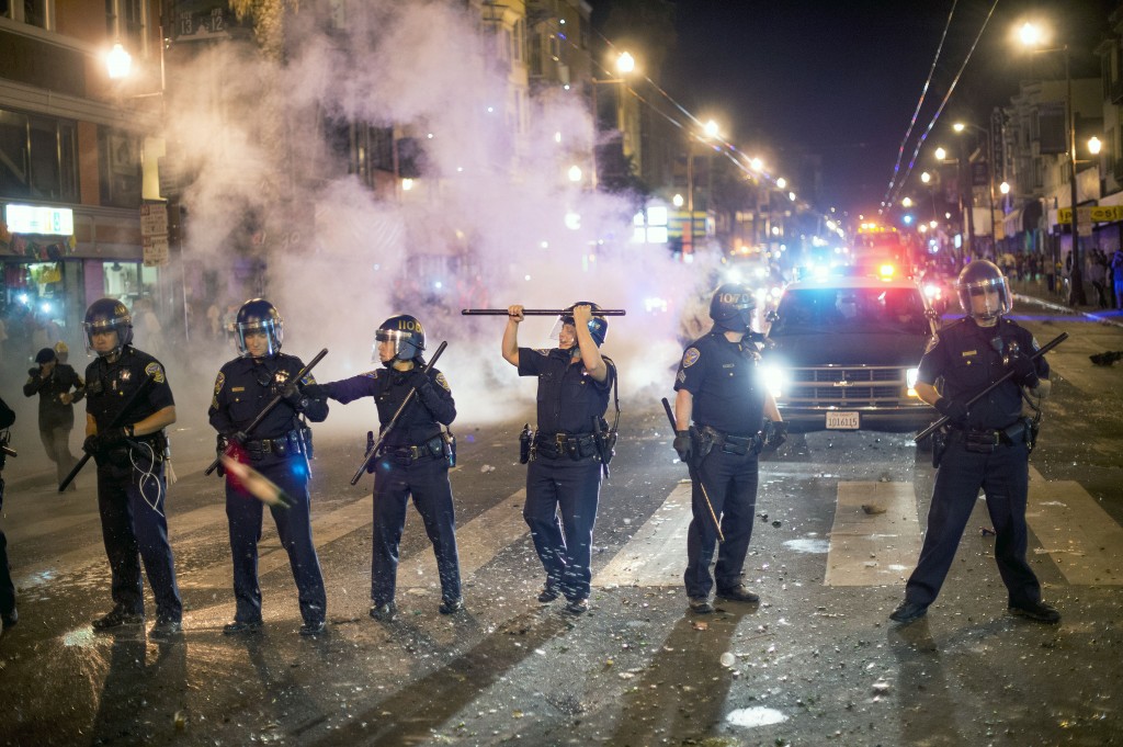 San Francisco police officers work to break up a large crowd who were celebrating after the San Francisco Giants won the World Series baseball game against the Kansas City Royals on Wednesday, Oct. 29, 2014, in San Francisco.  There were several reports of fires being set and violence breaking out after the Giants win. (AP Photo/Noah Berger)