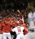 St. Louis Cardinals players celebrate after their 3-2 win over Los Angeles Dodgers in Game 4 of baseball's NL Division Series Tuesday, Oct. 7, 2014, in St. Louis as Los Angeles Dodgers right fielder Yasiel Puig, right, looks on. (AP Photo/Charles Rex Arbogast)